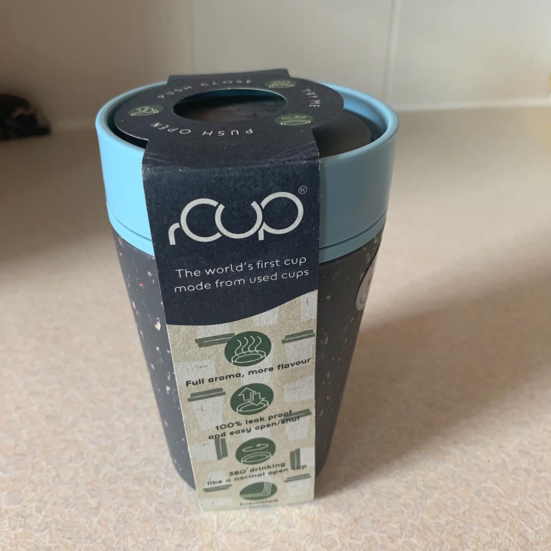 A tall cylindrical grey and teal plastic Reusable Coffee Cup on a white background.
