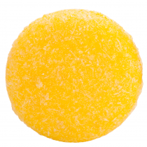 Five Ways I'm Trying To Be More Eco-Friendly A large circular bright yellow shampoo bar that has some pieces of Sea Salt embedded in it, on a white background.