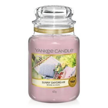 What I Thought of the Yankee Candle Advent House 2014 A tall glass jar full of some bright pink wax with a label that has Yankee Candle written in black writing, Sunny Daydream written in black writing, and a picture of a swinging hammock on it, on a white background.