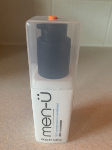 A short rectangular white plastic Bottle with a clear lid that has Men-ü written in bold black writing and Slick, smooth leave in conditioner written in bold blue writing on it, on a white background.