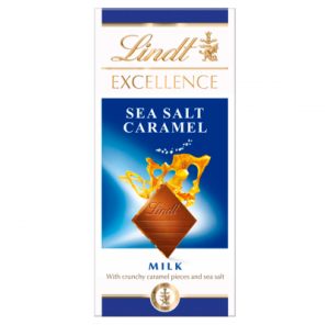 A tall rectangular light blue and white cardboard box that has Lindt written in bold gold writing, Excellence Milk Sea Salt & Caramel written in bold white writing, and a picture of a square piece of chocolate on it, on a white background.