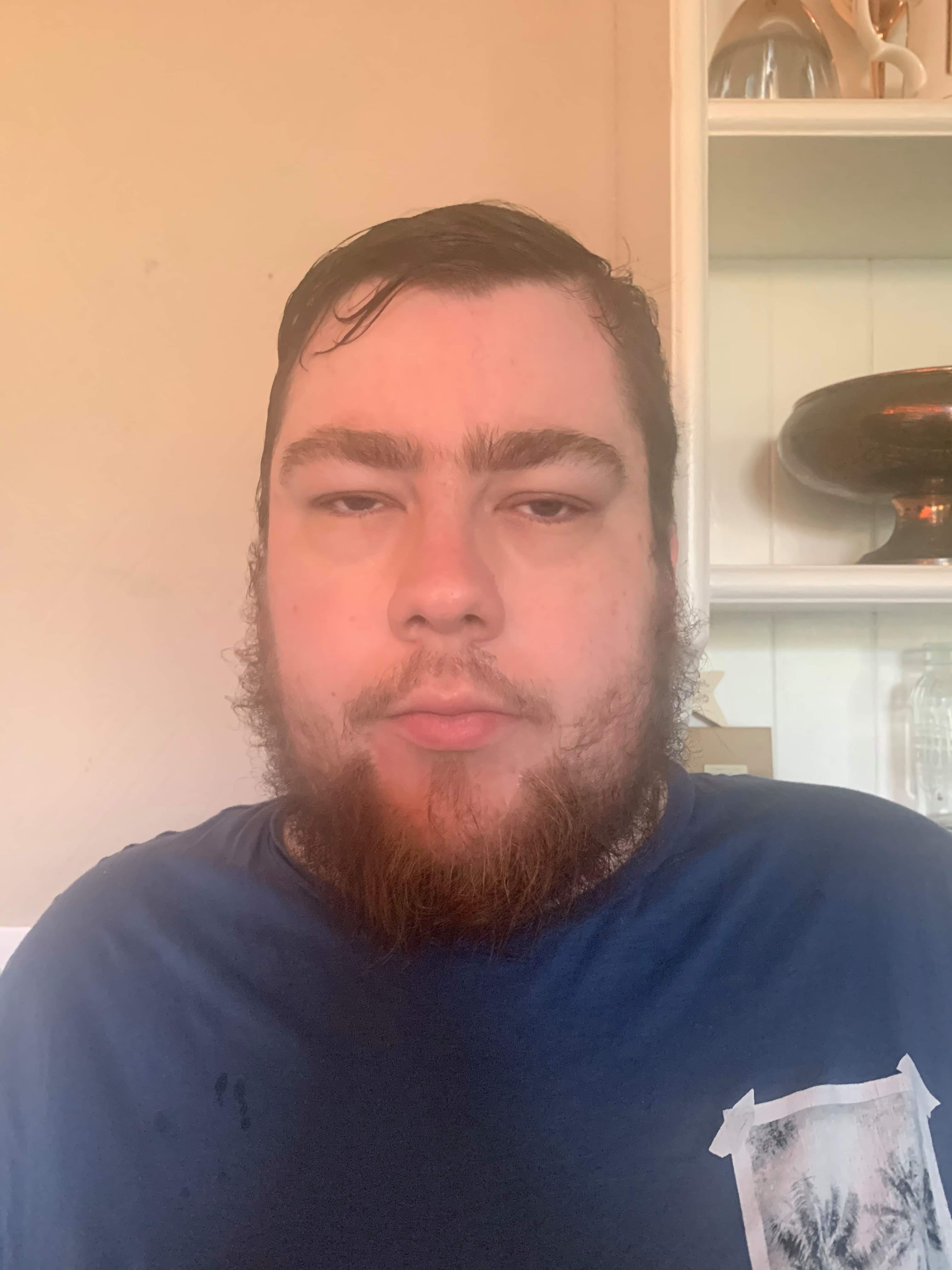 Shine Bright Like A Diamond | Sanctuary Spa Diamond Dust Refining Scrub Face Mask A tall bearded man wearing a bright blue t-shirt stood against a bright white wall.