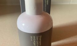A tall wide cylindrical white plastic bottle with a light grey label that has Sons DHT Blocker Shampoo written in bold white writing on it next to a tall white cardboard box that has Sons DHT Blocker Shampoo written in bold black writing on it, on a white background.