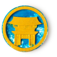 A large flat circular medium yellow Bath Bomb that has a picture of a bright yellow Temple and some bright blue clouds engraved on it, on a white background.