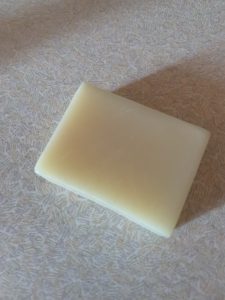 A small creamy white square block of soap, on a white background.