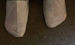 Me wearing a pair of bright white plastic socks stood on a dark grey carpet.