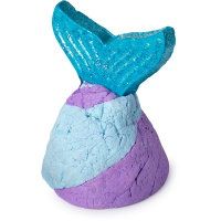 Fairytales Are Real | Lush Unicorn Horn Bubble Bar and Prince Charming Shower Cream A small shimmering bright blue and purple mermaid tail bubble bar that has a bright yellow cocoa butter fin attached to the bottom of it, on a white background.