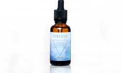 A short cylindrical brown glass bottle with a black rubber pipette lid and a white and gradient blue label that has runesilk elements earth beard oil written in bold black writing and a picture of a blue triangle on it, on a white background.