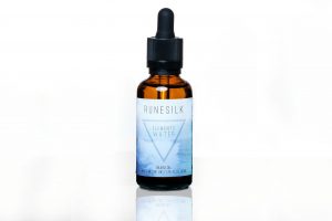 A short cylindrical brown glass bottle with a black rubber pipette lid and a white and gradient blue label that has runesilk elements water beard oil written in bold black writing and a picture of a blue triangle on it, on a white background.