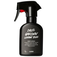 A tall black plastic kitchen spray bottle with a black label that has lush Dad's Garden Lemon Tree body spray written in bold white writing on it, on a white background.