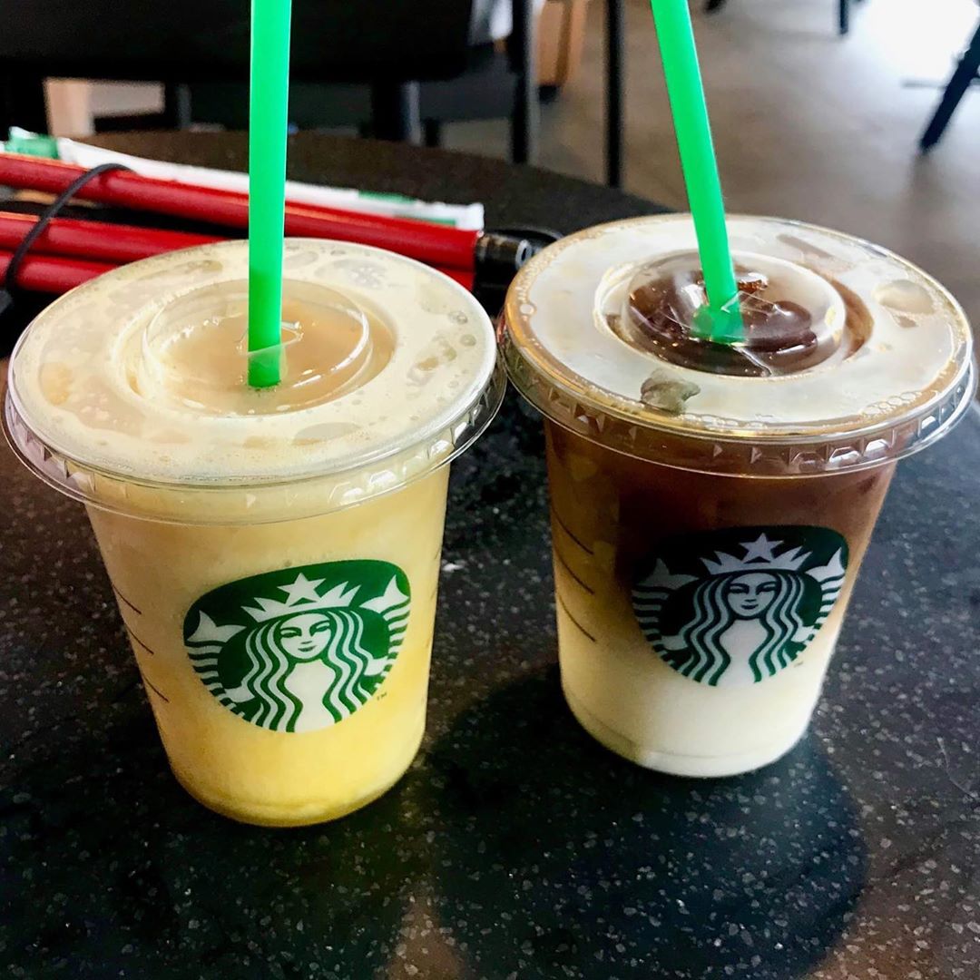 How To Make My 3 Favourite Starbucks Summer Menu Drinks At Home A short cylindrical clear plastic cup with a clear plastic lid Full of some bright orange liquid that has a green plastic straw coming out of the top of it on a light wooden table, on a white background.