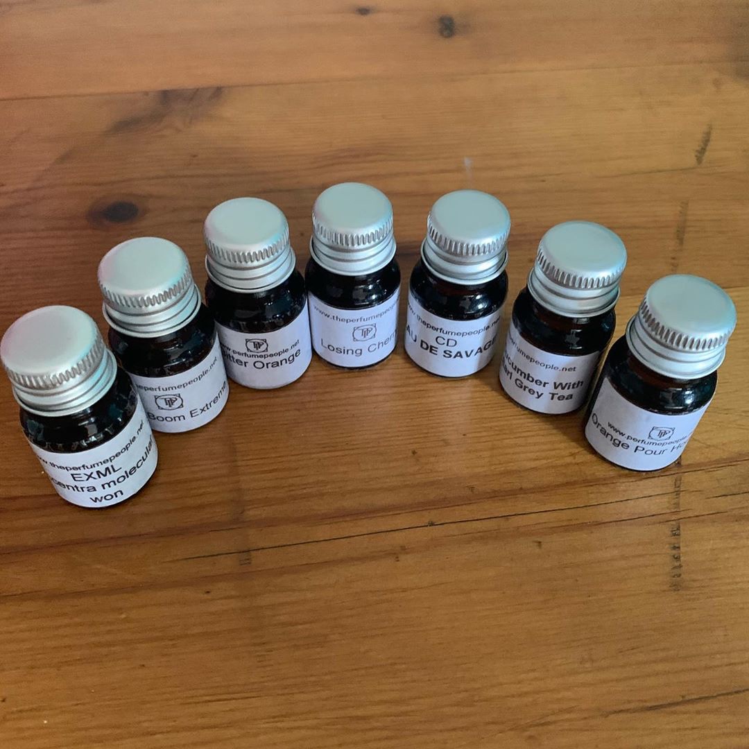 Even A Crowd Of People Can Smell Nice | The Perfume People Perfume Oils | Gifted A collection of seven short cylindrical clear glass jars full of some clear liquid with white labels that all have The Perfume People written in bold black writing on them, on a white background.