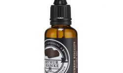 A short cylindrical dark green glass bottle with a black rubber pipette lid and a black label that has Arthur J Hawke Bourbon Biscuits Beard Oil written in bold white writing on it, on a white background.