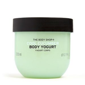 A short rounded rectangular clear plastic tub full of some pale turquoise liquid with a dark green lid that has The Body Shop Cool Cucumber Body Yoghurt written in dark green writing and some pictures of some bright green cucumbers on it, on a white background.