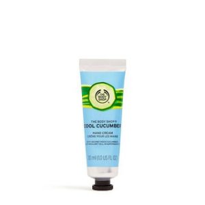 A small thin conical silver plastic tube with a dark green lid that has The Body Shop Cool Cucumber Hand Cream written in dark green writing and a picture of a large bright green cucumber on it, on a white background.