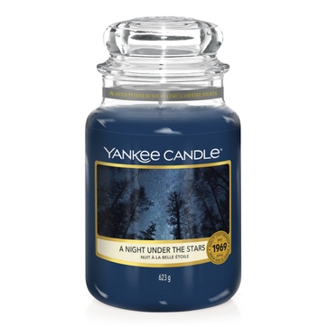Good Night Sweetheart, Still My Love Will Guide You | The Yorkshire Soap Company Night Night Sweetheart Tin Candle A tall glass jar full of some dark blue wax with a label that has Yankee Candle written in black writing, A Night Under The Stars written in black writing, and a picture of some fern trees against a clear starry night on it, on a white background.