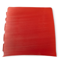 A large trapezium shaped block of dark orange soap that has Lush engraved on the side of it, on a white background.
