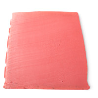 A large trapezium shaped block of bright red and pink swirled soap that has Lush engraved on the side of it, on a white background.