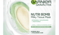 A tall rectangular bright white plastic pouch that has Garnier written in bold black writing, Nutri Bomb Almond & Hyaluronic Acid Tissue Mask written in smaller black writing, and a picture of a large circular puddle of bright white milk on it, on a white background.