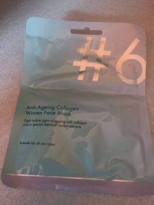 A tall rectangular white plastic pouch that has Poundland #6 Anti-Ageing Collagen Woven Face Mask written in dark grey writing on it, on a white background.