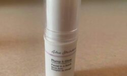 A short cylindrical white plastic tube with a white label that has Primark X Alex Steinherr Plump & Glow Facial In A Stick written in bold black writing on it, on a white background.