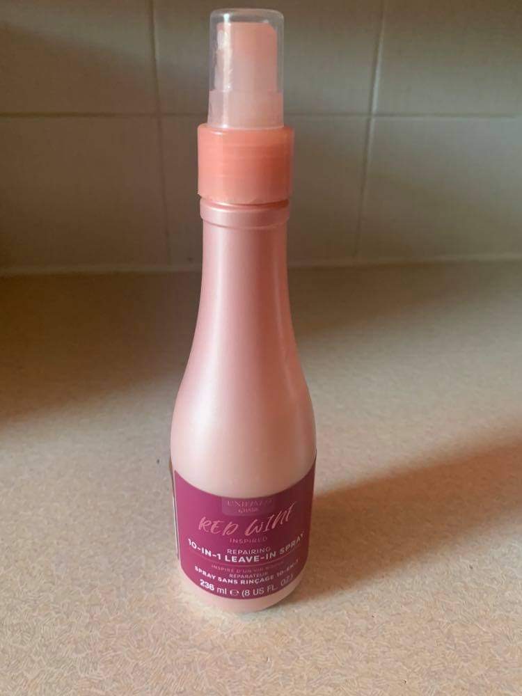 Who Knew Red Wine Was Also Good For Your Hair? | Hask Red Wine Repairing 10 In 1 Leave In Conditioning Spray A tall cylindrical dark pink Plastic Wine Bottle with a dark red label that has Hask Red Wine 10 In 1 Leave In Conditioning Spray written in bold white writing on it, on a white background.