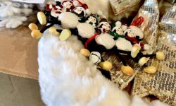 A collection of Christmas Decorations including some large white furry Snowflakes, a white circular furry Christmas Wreath with a Silver ribbon around it, a small rectangular wooden plaque that has some bells attached to the bottom of it, and some small Red and White wooden hearts, on a white background.