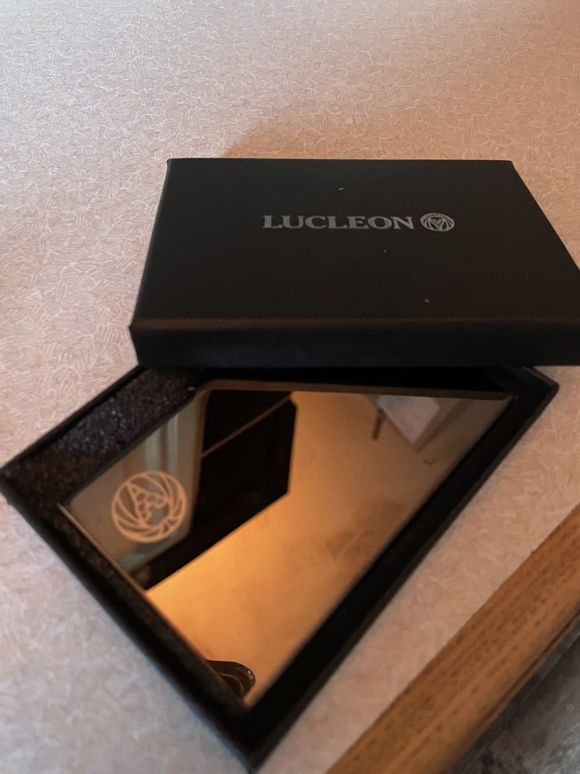 The Trendiest Card Holder In Denmark | Lucleon Black Stainless Steal Card Holder From Trendhim + Giveaway A small rectangular shiny black metal card holder inside a small brown cardboard box, on a white background.