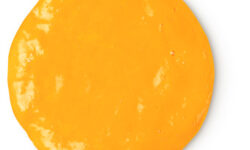 A medium circular puddle of creamy golden shower gel, on a white background.
