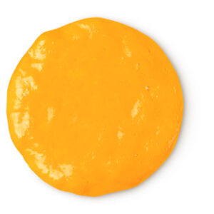 A medium circular puddle of creamy golden shower gel, on a white background.