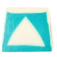A large trapezium shaped block of bright blue and light blue soap that has a picture of a slice of cake engraved on it, on a white background.