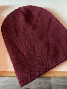 A large wine red knitted beanie hat, on a white background.