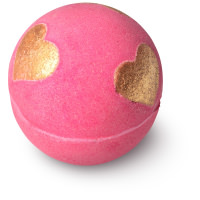 A large spherical bright pink bath bomb that has three gold glitter cocoa butter hearts embedded in it, on a white background.
