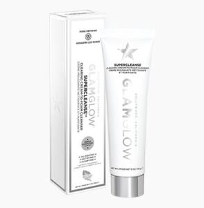 A tall thin conical white Plastic Tube with a silver Plastic Lid that has GlamGlow SuperCleanse™ Cream To Foam Cleanser written in bold black writing on it next to a tall rectangular white cardboard box that has GlamGlow SuperCleanse™ Cream To Foam Cleanser written in bold black writing and a picture of a silver star on it, on a white background.