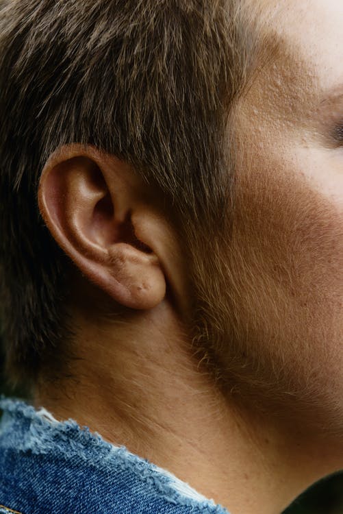 Five Things I Do To Avoid Getting An Ear Infection | Ad A tall white man wearing a navy blue shirt that has his Head to the side so that you can see his ear, on a white background.