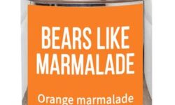 A short cylindrical silver metal tin with a bright orange label that has bird & blend tea company Bears Like Marmalade Loose Leaf Tea written in bold white writing on it, on a white background.