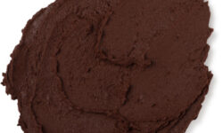 A medium circular puddle of thick dark brown face mask, on a white background.