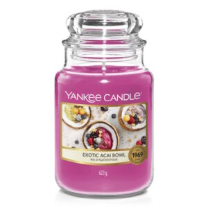 A tall cylindrical Glass Jar full of some light purple wax with a label that has Yankee Candle written in white writing, Exotic Acai Bowl written in black writing, and a picture of a bowl full of some pale purple smoothie that's topped with some various different fruits on it, on a white background.