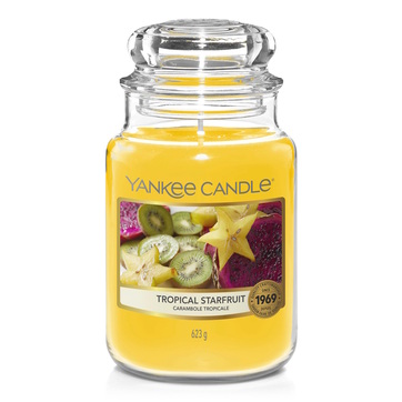 What I Thought of the Yankee Candle Advent House 2014 A tall cylindrical Glass Jar full of some bright yellow wax with a label that has Yankee Candle written in white writing, Tropical Starfruit written in black writing, and a picture of some cut up pieces of yellow starfruit on it, on a white background.