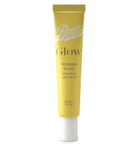 A long thin cylindrical bright yellow Plastic tube that has boots written in bold white writing and glow pineapple serum written in bold gold writing on it, on a white background.