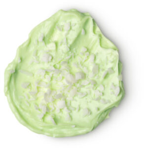 A medium circular puddle of light green body butter that has some chunks of shea butter running through it, on a white background.