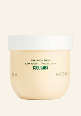 A short rounded rectangular clear plastic tub full of some pale yellow liquid with a white plastic lid that has The Body Shop Cool Daisy Body Yogurt written in dark green writing and some pictures of some pale yellow daisies on it, on a white background.