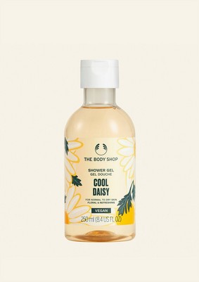 Smelling Like A Shop Full Of Daisies | The Body Shop Cool Daisy Range A tall cylindrical clear plastic bottle full of some pale yellow liquid with a white plastic lid and a pale yellow label that has The Body Shop Cool Daisy Shower Gel written in dark green writing and a picture of some pale yellow Daisies on it, on a white background.