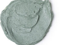 A medium circular puddle of thick dark green face mask, on a white background.