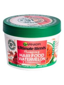 A short cylindrical white plastic tub with a bright green lid and a bright green label that has Garnier Ultimate Blends Hair Food Watermelon Hair Treatment written in bold black writing and a picture of a Watermelon on it, on a white background.
