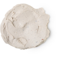 A medium circular puddle of creamy white face mask that has some pieces of dried dates running through it, on a white background.