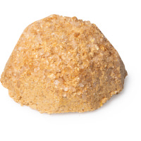 I'm Going To Fly Away On A Mountain Of Salt | Lush Flyway Salt Scrub With Coconut & Himalayan Rock Salt Scrub With Strawberry & Ginger A large circular mound of sandy yellow salt scrub, on a white background.