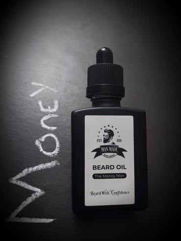 Do I Look Like I'm Made Of Money Man? | Man Made Beard Company The Money Man Beard Oil | Gifted A short rectangular brown glass Bottle with a black rubber pipette lid and a white label that has Man Made Beard Company The Money Man Beard Oil written in bold black writing and a picture of a man with a black beard on it, on a white background.