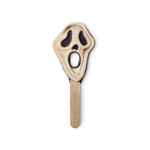 A large white mask shaped bubble bar that has some black eyes and a black hole in the middle of it on a light wooden stick, on a white background.