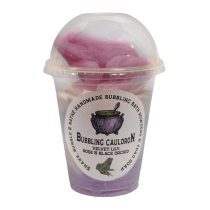 A tall cylindrical clear plastic cup full of some bright purple powder with a clear plastic dome lid and a white label that has The Yorkshire Soap Company Bubbling Cauldron Shake, Bubble & Bathe written in bold black writing and a picture of a bubbling black Cauldron on it, on a white background.